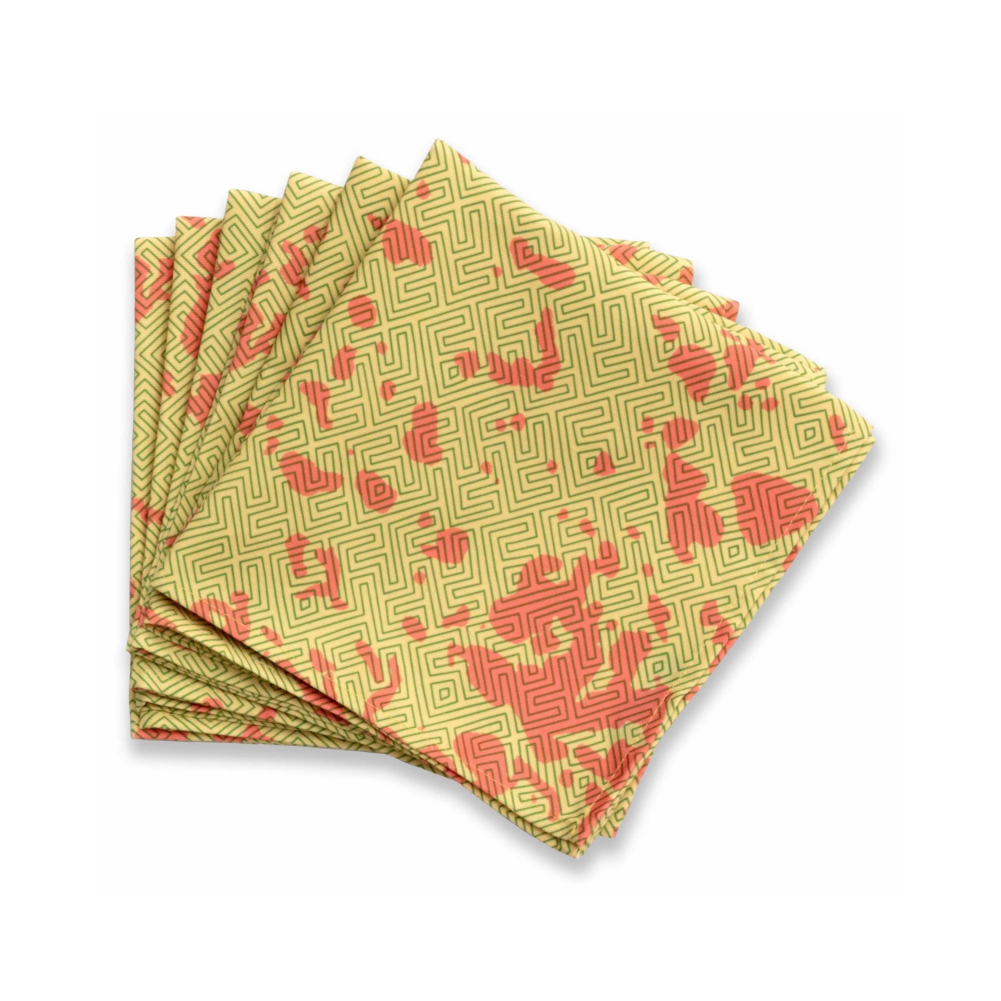 Bright patterned cloth napkin with quarter-inch hem. Base color is mustard yellow with random splotches of brick red, overlaid with a thin-lined, maze-like pattern in rosemary green. The back is the base color with small, discreet dark grey logo on bottom left-hand side. View: 6 napkins folded into quarters and fanned out, with pattern side exposed.