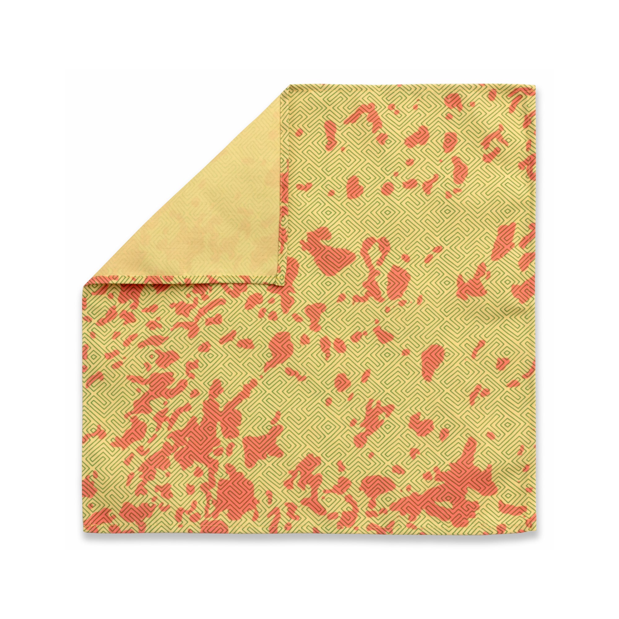 Bright patterned cloth napkin with quarter-inch hem. Base color is mustard yellow with random splotches of brick red, overlaid with a thin-lined, maze-like pattern in rosemary green. The back is the base color with small, discreet dark grey logo on bottom left-hand side. View: 1 napkin laid flat, with pattern side exposed and the top left corner folded down to expose back side.