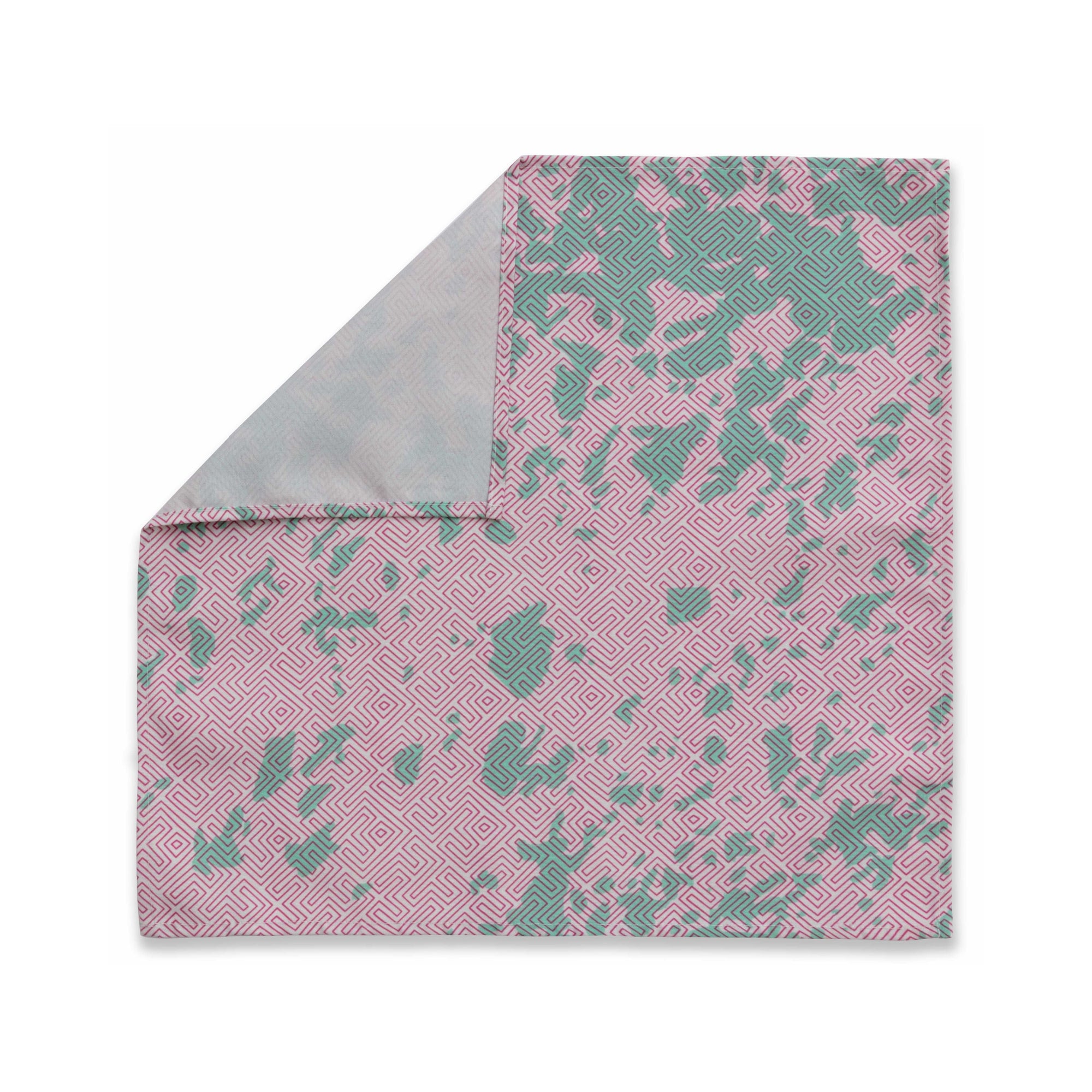 Bright patterned cloth napkin with quarter-inch hem. Base color is pale pink with random splotches of pale mint green, overlaid with a thin-lined, maze-like pattern in raspberry red. The back is the base color with small, discreet dark grey logo on bottom left-hand side. View: 1 napkin laid flat, with pattern side exposed and the top left corner folded down to expose back side.